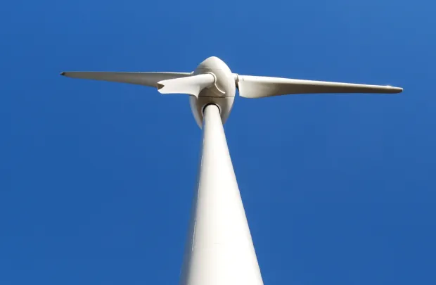 A wind turbine with as blue sky in the background - Scotland’s Our Power campaign urges Holyrood parties to ensure communities benefit from the renewable energy boom through public investment, jobs, and local ownership.